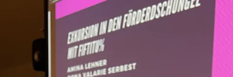 Präsentationstext auf Leinwand, seitliche Aufnahme.