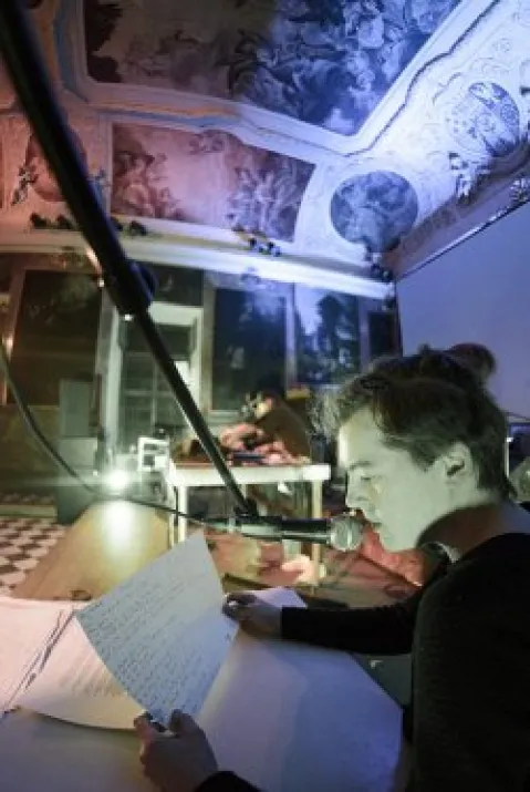 In Mikrofon sprechende Person in kunstvoll dekoriertem Raum.