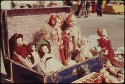Antike Puppen in einem offenen Koffer auf einem Flohmarkt.