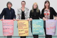 Vier Frauen halten bunte, feministische Plakate mit Botschaften.