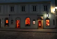 Eingang eines Gebäudes bei Nacht, Fenster leuchten orange.