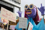 Große Puppe und Schilder mit feministischen Botschaften bei einer Demonstration.