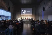 Podiumsdiskussion mit Publikum in einem modernen Veranstaltungsraum.
