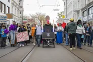 Demonstration von Aktivist*innen mit bunten Schildern auf einer Stadtstraße.