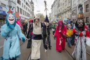 Menschen in bunten Kostümen und Masken bei einem Straßenumzug.