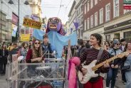 Menschen bei einer feministischen Demo, mit Musik und farbenfrohen Schildern in einer Stadtstraße.
