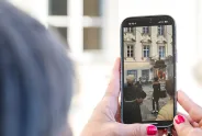 Hand hält Smartphone mit Foto von Frauenversammlung im Freien.