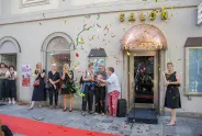 Menschen feiern vor einem Gebäude mit der Aufschrift "Salon", Konfetti in der Luft.