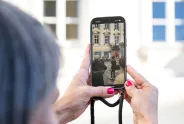 Smartphone-Foto einer Straßenszene, Frau mit roten Nägeln im Fokus.