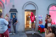 Person in auffälligem Kostüm bei Veranstaltung, umgeben von applaudierenden Menschen.