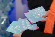 Person hält Flyer mit feministischen Forderungen in Blau und Pink.