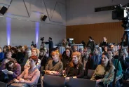 Publikum in einem Konferenzraum, aufmerksam lauschend.