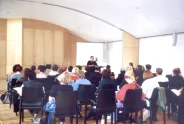 Menschen in einem Seminarraum, Vortragende vorne, Publikum zuhört.