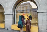 Drei Personen mit farbigen Mützen betrachten eine Schaufensterauslage.
