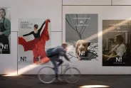 Posters an einer Wand, diffuse Bewegungsunschärfe eines Radfahrers im Vordergrund.
