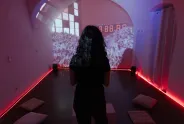 Person in dunklem Raum, Video-Projektion an der Wand.