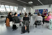 Frauen sitzen im Kreis in einem hellen Raum und diskutieren.