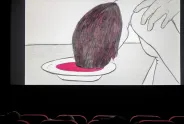 Illustration einer Person mit Kopf über einem Teller in einem Kinosaal.