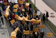 Demonstration mit gelben Bannern, Plakaten und bunter Kleidung auf einer Straße.