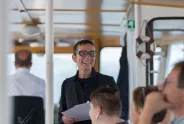 Eine Person hält lächelnd ein Papier in der Hand, während sie auf einem Boot steht.