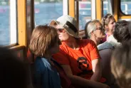 Menschen auf einem Boot, eine Person trägt ein rotes feministisches T-Shirt.