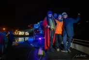 Menschen in Winterkleidung auf einem beleuchteten Boot bei Nacht.