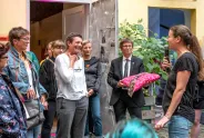 Menschen in einem Innenhof, Frau mit Mikrofon spricht zu lächelnder Gruppe.