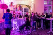 Menschen bei einer feministisch dekorierten Veranstaltung, lila Beleuchtung.