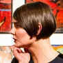 Frau vor farbigen Kunstwerken, nachdenklich.