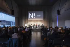 Podiumsdiskussion mit Publikum in einem modernen Veranstaltungsraum.
