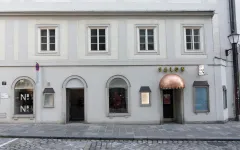 Salon-Gebäude mit grauer Fassade und doppeltürigen Fenstern.