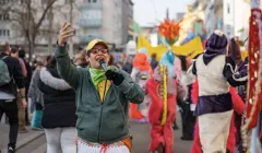 Person in bunter Parade spricht begeistert ins Mikrofon.