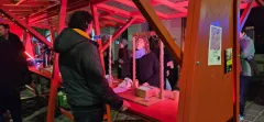 Menschen an einem roten Infostand bei Nacht.