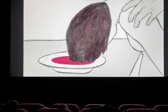 Illustration einer Person mit Kopf über einem Teller in einem Kinosaal.