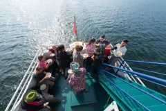 Gruppe von Menschen isst und unterhält sich auf einem Boot auf dem Wasser.