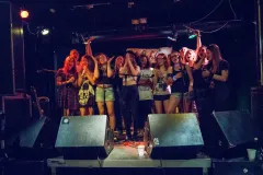 Frauen auf Bühne, lächeln und feiern, in einem Club mit dunkler Beleuchtung. Fotografiert.