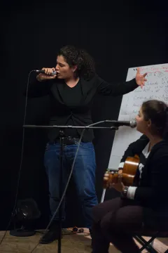 Zwei Personen bei einer Musikprobe, eine singt, die andere spielt Gitarre.