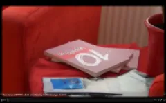 Rotes Sofa mit Büchern und Tassen auf einem Tisch.