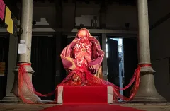 Rote Skulptur in rotem Licht zwischen Säulen.