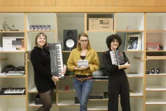 Drei Personen mit Keyboards in einem Musikraum.