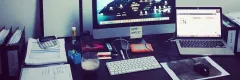 Arbeitsplatz mit zwei Computern, Tastatur, Maus und Unterlagen.