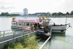 Touristenboot am Ufer eines Flusses, Menschen steigen ein.