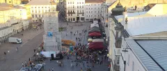 Stadtplatz mit Menschenmenge, Zelten und Bühne bei Sonnenuntergang.