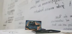 Stempel auf Tisch vor beschrifteter Wand, Unschärfe im Hintergrund.