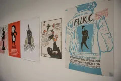 Posterreihe an einer Wand mit Grafiken und Text in verschiedenen Stilen und Farben.